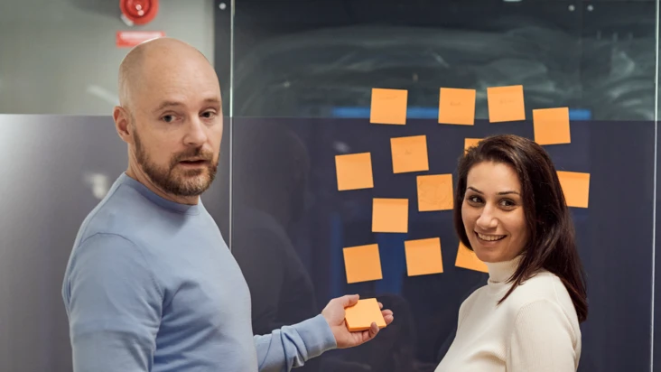 En man och en kvinna sätter upp postit-lappar på en vägg.