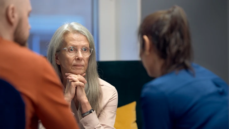 Tre personer i förtroligt samtal lyssnar uppmärksamt på varandra.