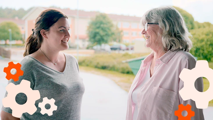 En yngre och en äldre kvinna ler mot varann i samförstånd.