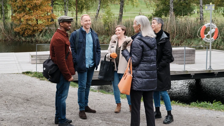 En grupp kollegor står utomhus och samtalar med varandra.